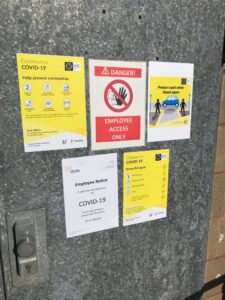 Signage on doors to Industrial Packaging factory about COVID19 safety measures