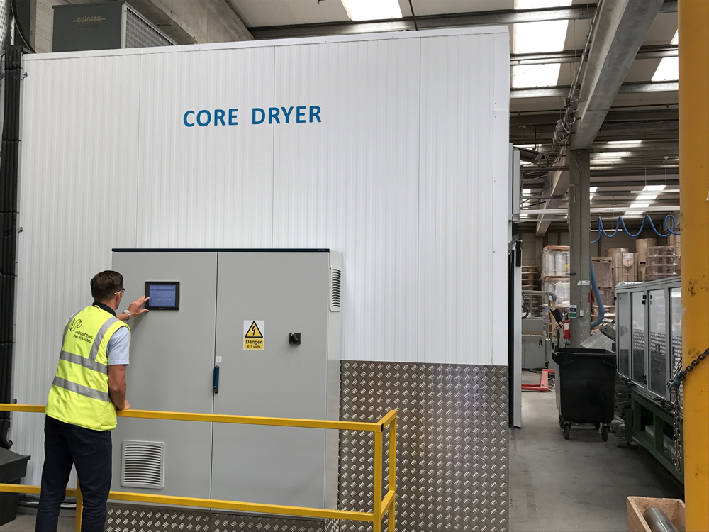 A machine operator programming a cardboard core drying machine